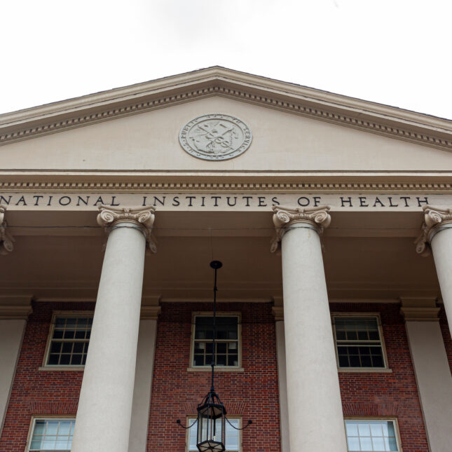 View of the main historical building (Building 1) of the National Institutes of Health (NIH) inside Bethesda campus. U.S. Public Health Service seal is seen on top of it – politics and policy coverage from STAT