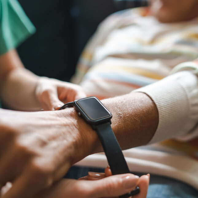 a doctor wraps a smart watch around a patient's wrist
