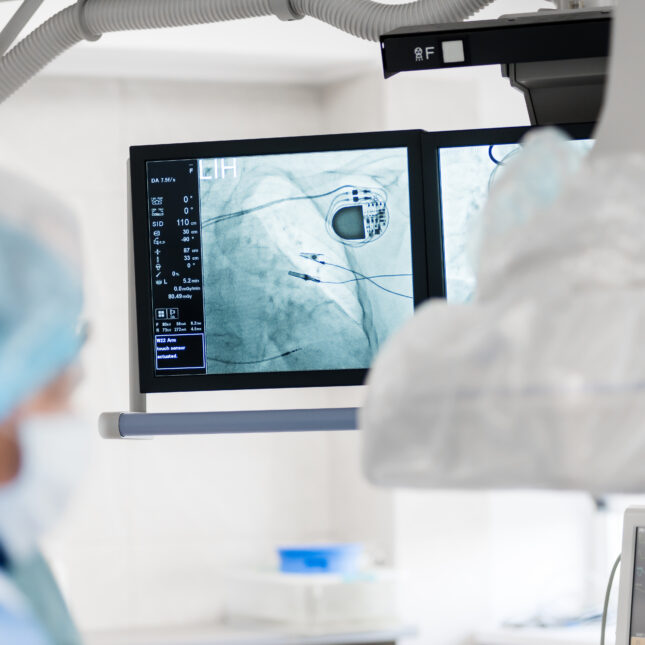 Surgeons look over an x-ray monitor showing an implanted pacemaker — health tech coverage from STAT