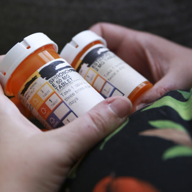 A photograph of hands holding bottles of medications for hormone replacement therapy as part of the gender affirming care of a trans woman at home in Orlando Fla., May 27, 2023.