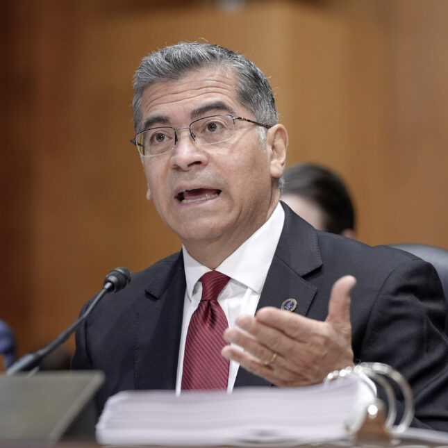 Xavier Becerra gestures with one hand while testifying during a Senate Finance Committee hearing — politics coverage from STAT