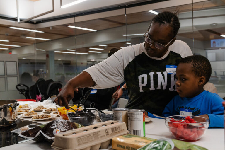 Latisha and her son serve themselves fresh fruit during a class on anemia and how to prepare accessible, iron-rich foods in the Teaching Kitchen at Boston Medical Center. -- health coverage from STAT