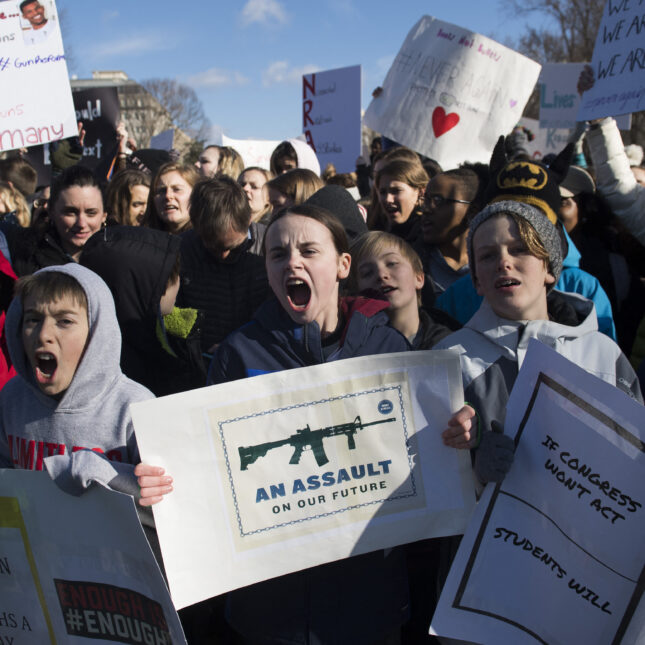 A group of students raise signs to protest gun violence. The children in the center hold a sign that reads "AN ASSAULT ON OUR FUTURE" — first opinion coverage from STAT